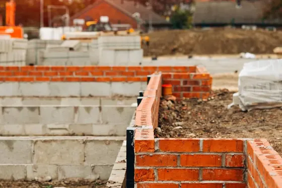 Rozestavěné základy domu z cihel a betonových tvárnic na staveništi.
