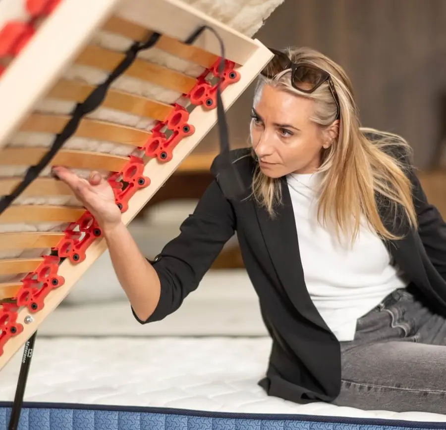 Žena zvedá lamelový rošt a zespodu kontroluje stav lamel a jejich pouzder.